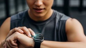 Person wearing fitness tracker smartwatch checking health stats and AI coaching recommendations on screen