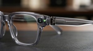 Macro shot of the outer hinge of Google's AI glasses highlighting the seamless integration of the camera lens and a tiny active privacy LED indicator.